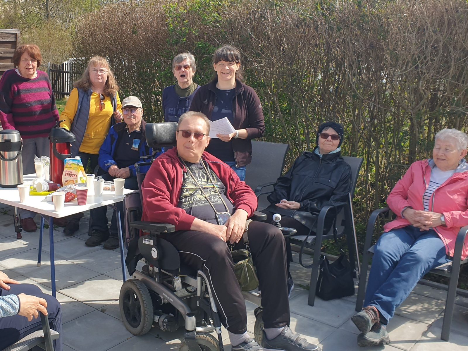 Gruppe sitzt gemeinsam im Garten